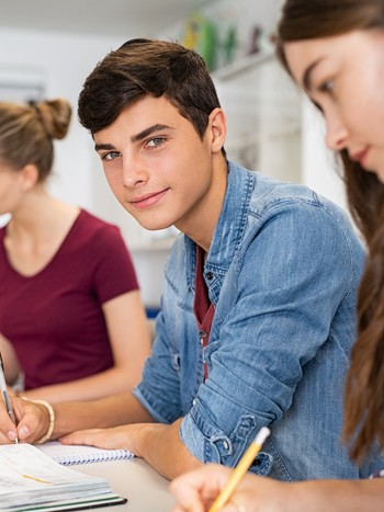 German teacher assisting a student in the classroom during a German exam