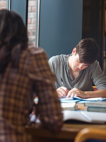 Étudiant préparant un examen d'allemand à la bibliothèque.