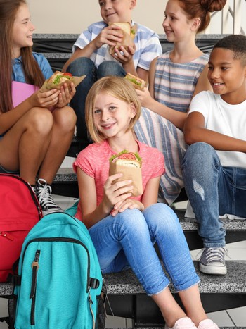 Schoolchildren practicing German while eating sandwiches at lunch break