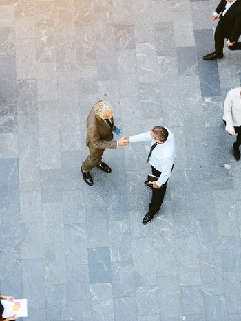 Businessmen doing business in German and shaking hands in a crowded office hall