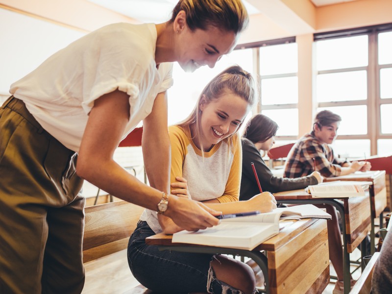 Professeur d'allemand aidant une élève en classe pendant un examen d'allemand.