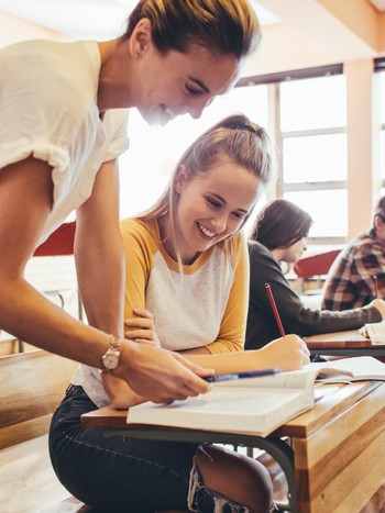 German teacher assisting a student in the classroom during a German exam