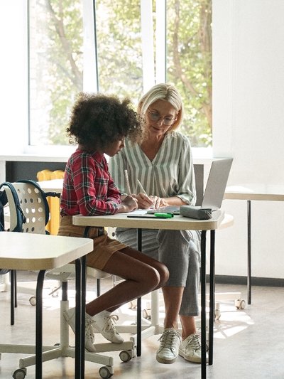 Un répétiteur d’allemand aidant un étudiant à faire ses devoirs dans une salle de classe.