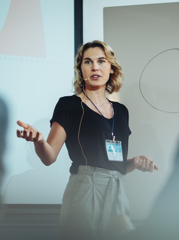 Femme d'affaires prenant la parole lors d'une conférence devant un public germanophone.